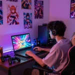 Gamer enjoying free porn games on a laptop in a cozy room with LED lighting.