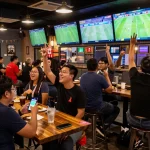 Xoilac fans enjoying live football matches at a sports bar with vibrant atmosphere and betting apps.